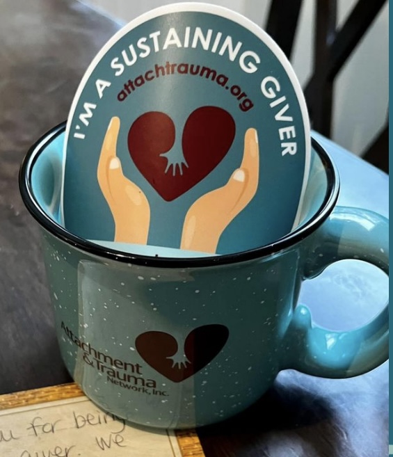 Green camp mug with ATN logo and sticker stuck in the meg. Mug goes to Sustaining Givers who donate $50 or more a month.